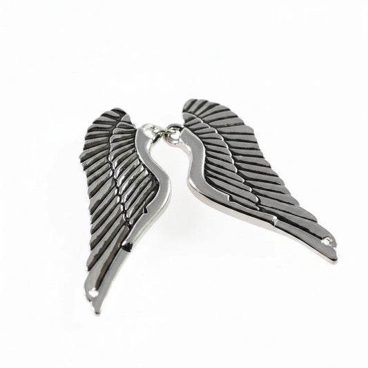 A pair of metallic angel wing charms with a polished silver finish, displayed against a plain white background.