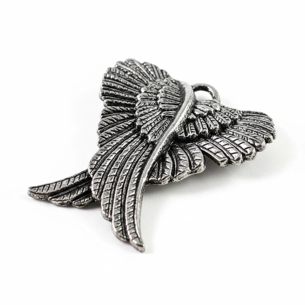 An antique silver metal angel wing pendant or charm, featuring detailed feather textures and a polished central bar, set against a plain white background.