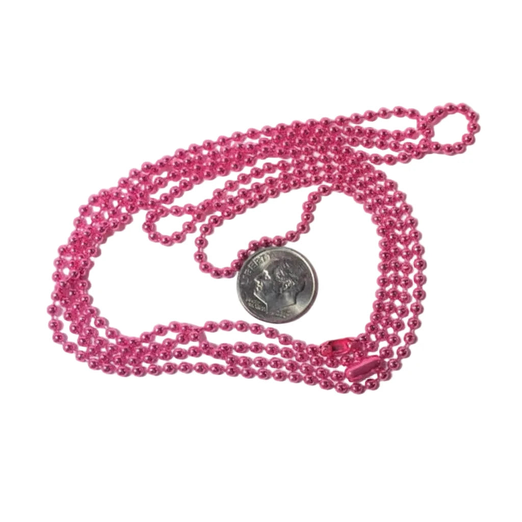A pink beaded necklace with a small silver coin placed on top for scale, photographed on a plain white background.