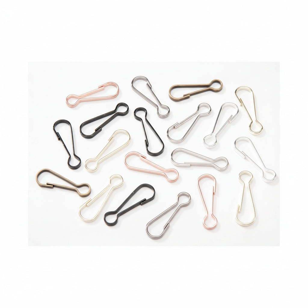 A set of small metal carabiner clips scattered on a plain white background, shown in multiple finishes including black, silver, rose gold, bronze, and gold.