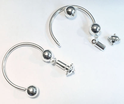 Silver-toned curved hoop earrings with spherical bead details and a small dangling charm, shown on a plain white background.