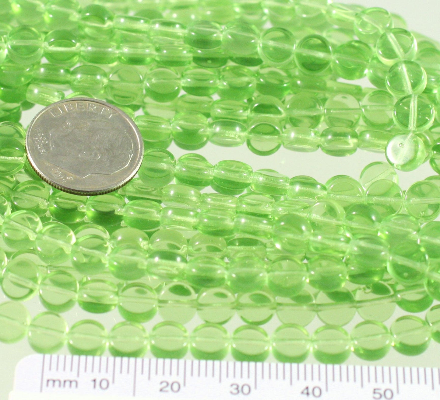 Green beads with a coin and ruler for size reference