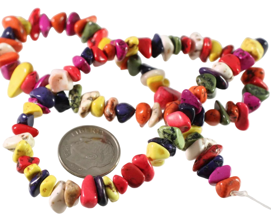 A strand of colorful tumbled stone chips beads in various shapes and colors, shown next to a US quarter coin for scale on a white background.