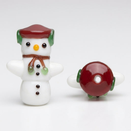 A festive glass bead shaped like a snowman wearing a red hat and brown scarf, shown alongside its back view which features a red circular top with green and white glass wings, on a plain white background.