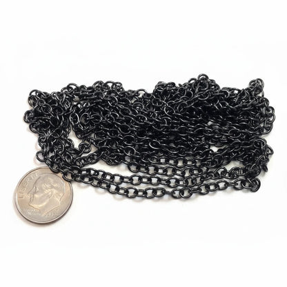 A coiled length of black metal chain links, shown next to a US quarter coin for scale, on a plain white background.