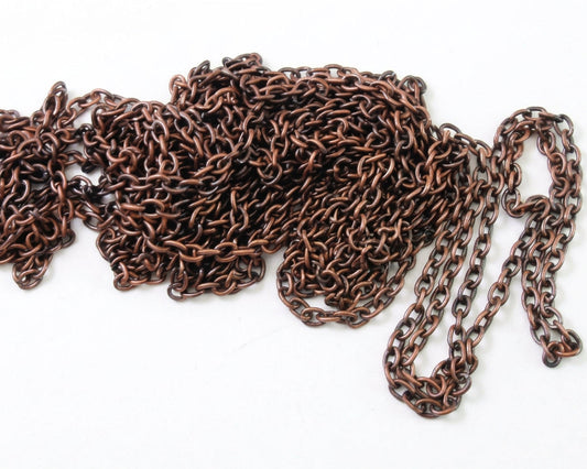 A close-up of a dark COPPER metal chain laid out on a white background, with a U.S.