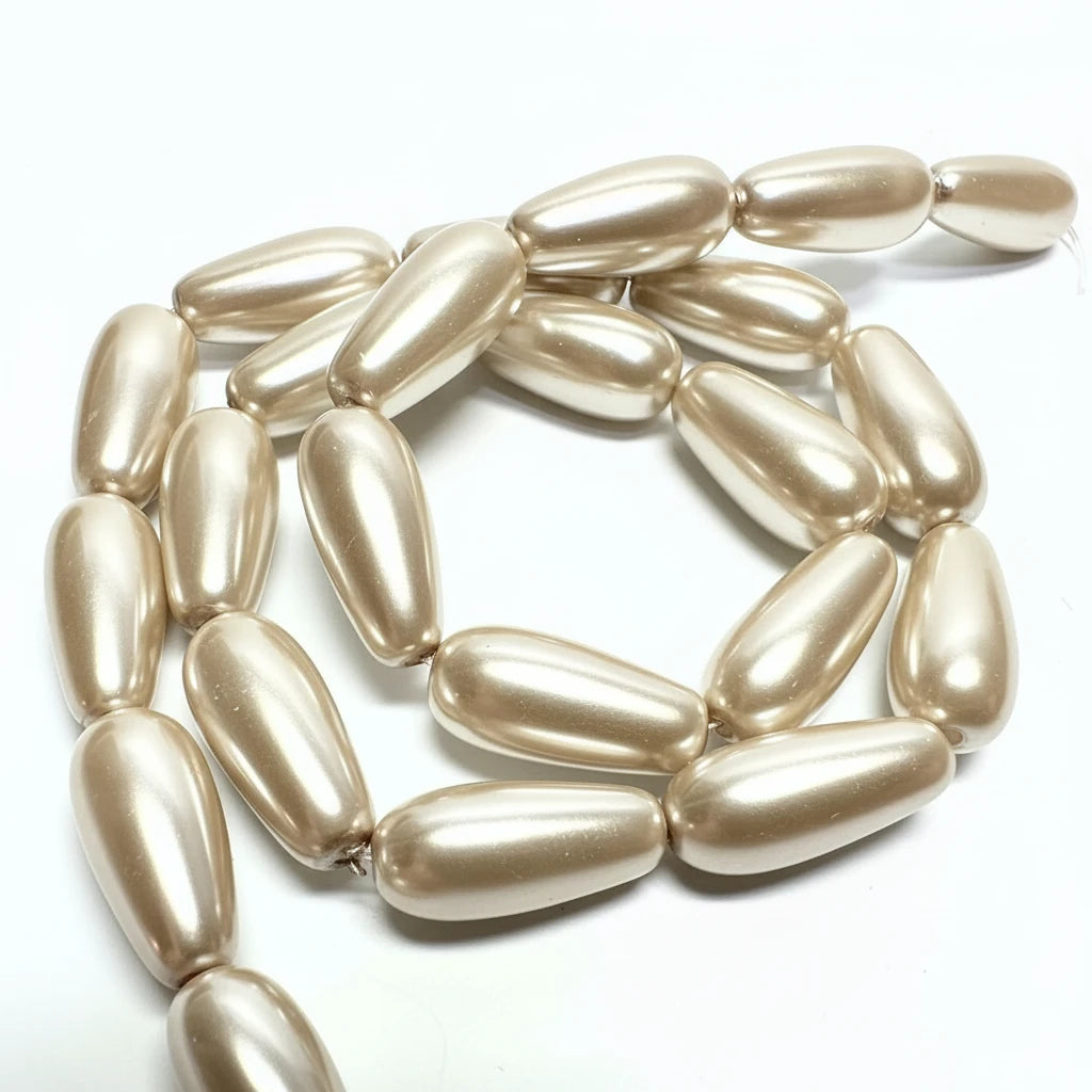 A strand of metallic champagne-gold teardrop beads with a pearlescent finish, arranged in a loose spiral on a plain white background.