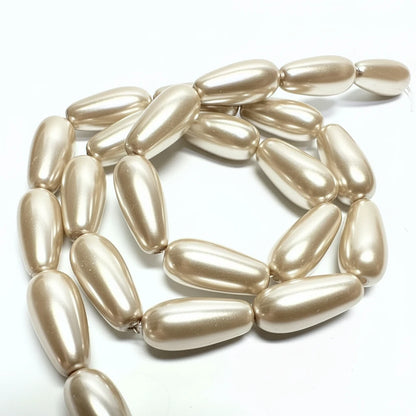 A strand of metallic champagne-gold teardrop beads with a pearlescent finish, arranged in a loose spiral on a plain white background.