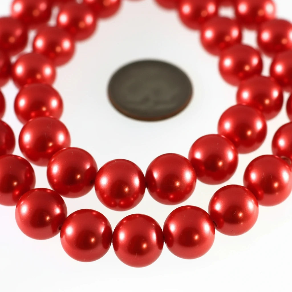 Red glossy round beads strung together on a white background, with a dark coin used for scale.