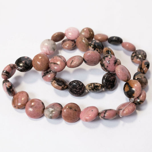 A strand of polished pink and black tourmaline beads with natural marbling, arranged in a loose circle on a white background.