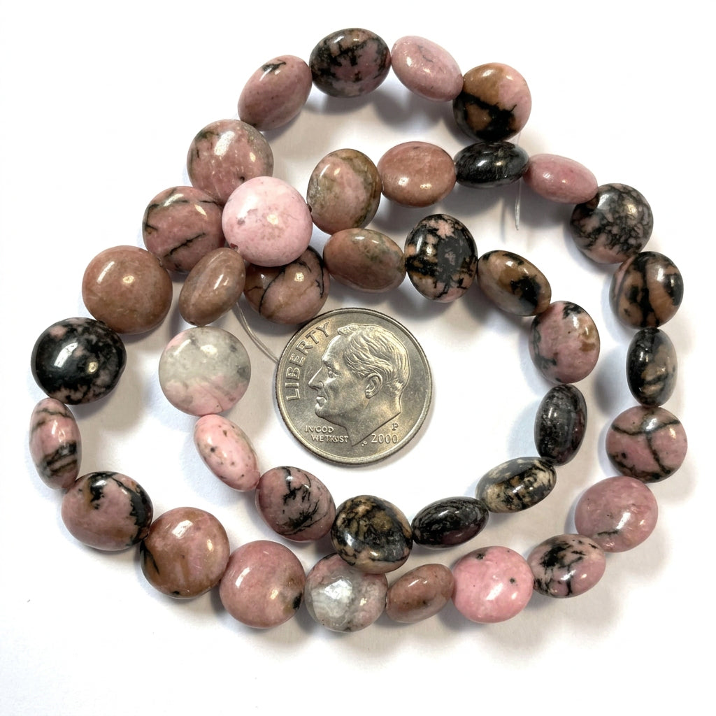 Pink and black tourmaline beads on a white background with a US quarter coin for scale.