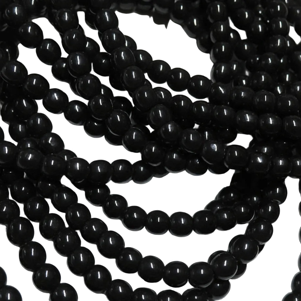 Black glossy round beads strung in multiple strands, photographed close-up against a white background.