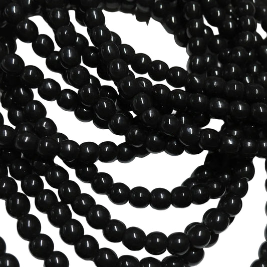 Black glossy round beads strung in multiple strands, photographed close-up against a white background.