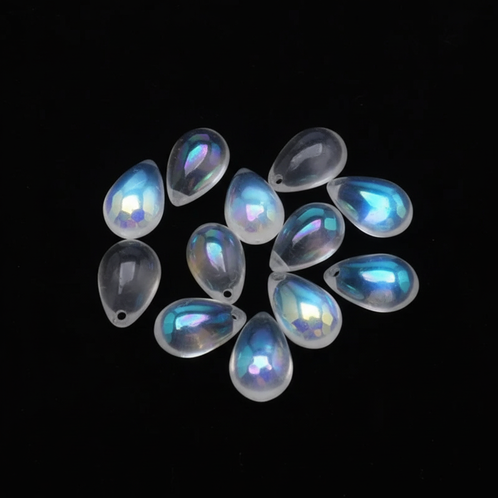 Ten iridescent teardrop-shaped cabochon beads with a white base and blue-purple holographic sheen, arranged on a solid black background.
