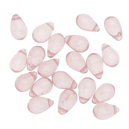 A group of small, teardrop-shaped translucent pink glass beads scattered on a plain white background.