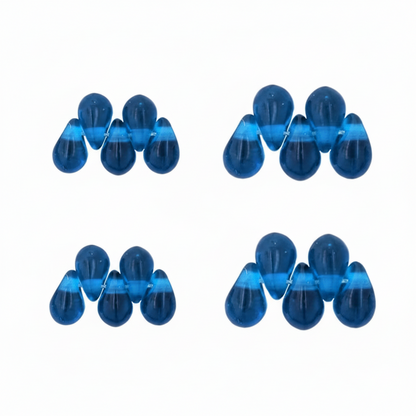 Four clusters of small translucent blue teardrop-shaped beads arranged in a 2x2 grid on a plain white background.