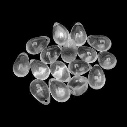 A pile of clear teardrop-shaped glass beads with small holes, shown on a solid black background.