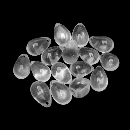 A pile of clear teardrop-shaped glass beads with small holes, shown on a solid black background.