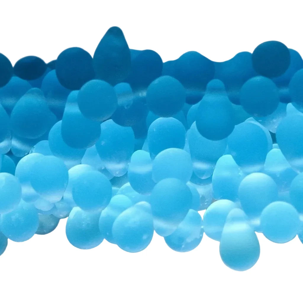 A close-up of translucent blue silicone gel beads arranged in rows on a neutral light gray background.