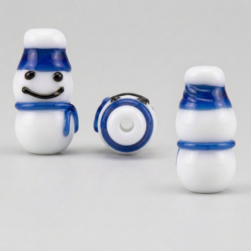 Three views of a small snowman-shaped accessory, likely a bead or charm, on a plain white background. The figure is white with a blue hat, blue scarf, and black facial features.