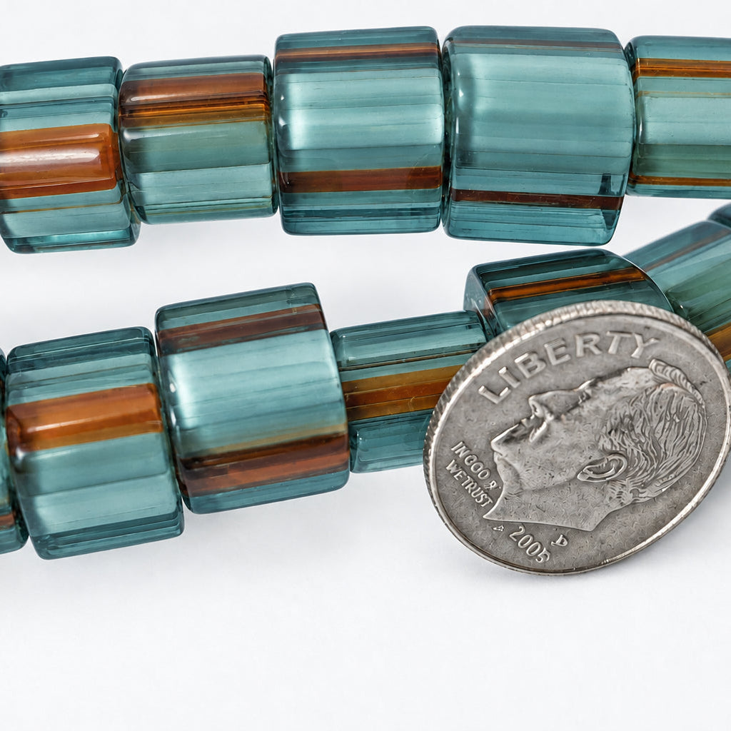 Chunky translucent square beads with alternating bands of smoky teal, light blue-green, and reddish-brown, shown next to a silver coin for scale on a white background.