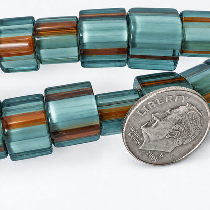Chunky translucent square beads with alternating bands of smoky teal, light blue-green, and reddish-brown, shown next to a silver coin for scale on a white background.