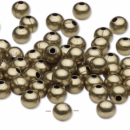 A pile of metallic gold round spacer beads with central holes, scattered on a plain white background.