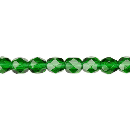 A close-up horizontal shot of faceted green glass beads on a plain white background.