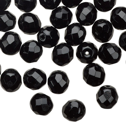 Black faceted round beads scattered on a plain white background.