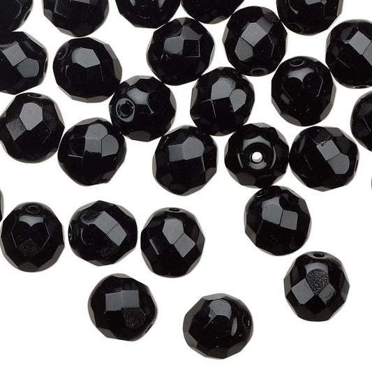 Black faceted round beads scattered on a plain white background.