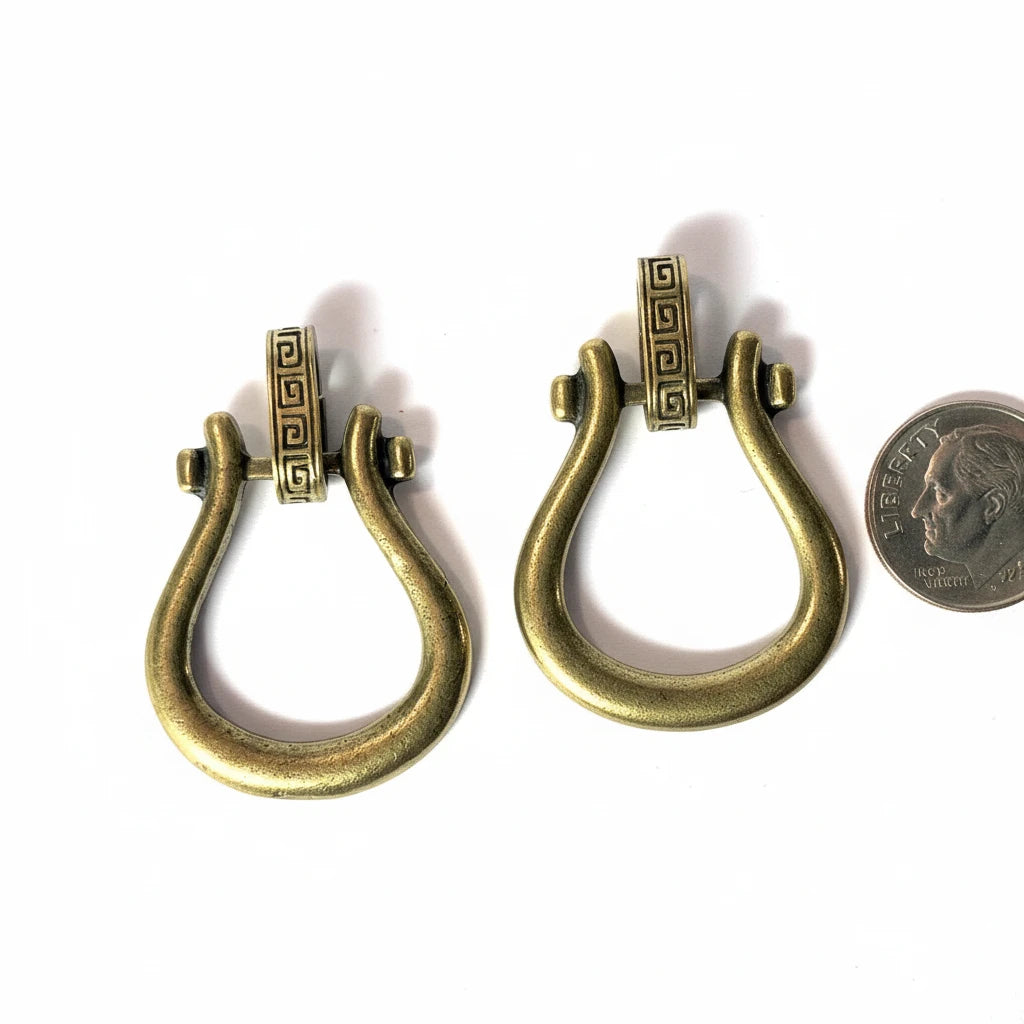 Two antique bronze metal lobster clasp findings shown side-by-side on a white background, with a US quarter coin on the right for scale.