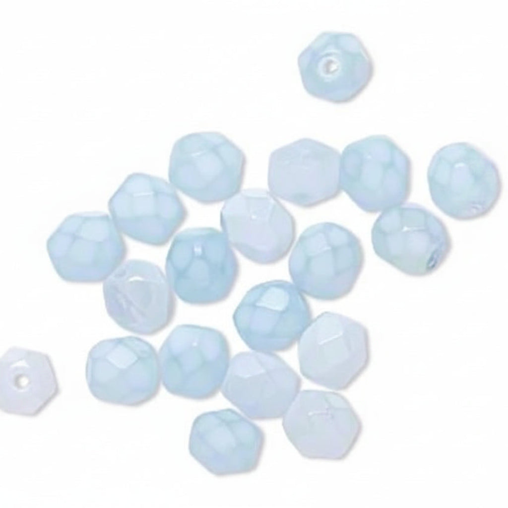 A group of small faceted glass beads in a pale icy blue color scattered on a plain white background.