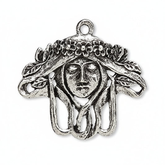 An antique silver-tone metal charm shaped like a Medusa head with flowing hair and a decorative headdress, shown on a plain white background.