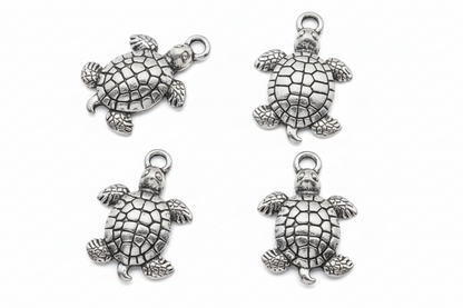 Four silver sea turtle charms with detailed textured shells, arranged in a 2x2 grid on a plain white background.