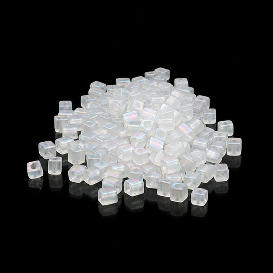 A pile of small translucent square beads with a central hole, shown on a black reflective surface.