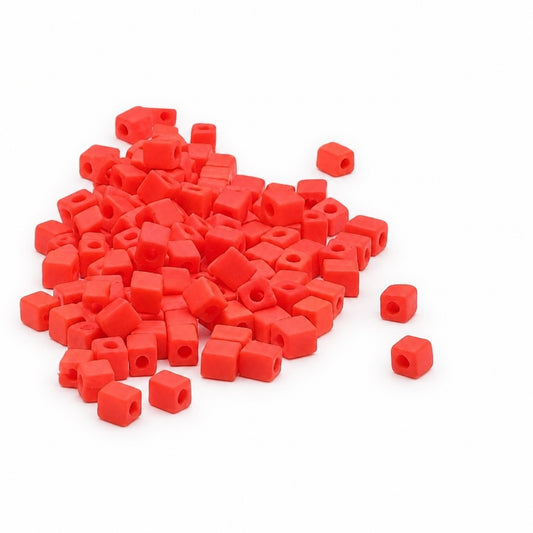 Bright ORANGE cube beads with central holes, scattered on a plain white background.
