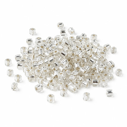 A pile of small clear seed beads with silver-toned metal spacers, scattered on a plain white background.