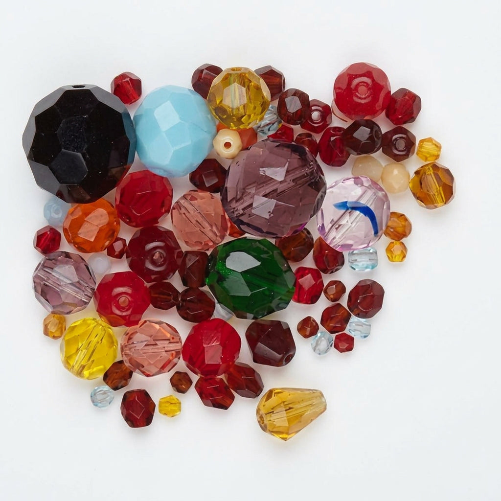 A pile of faceted glass beads in assorted colors and sizes, including red, green, purple, blue, yellow, and clear, scattered on a white background.