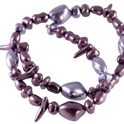A multi-strand beaded necklace featuring irregular, polished purple and violet beads with a glossy, metallic finish, arranged in a spiral on a plain white background.