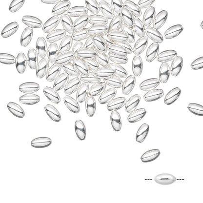 A pile of small, polished silver oval beads scattered on a white background, with a small inset diagram at the bottom right showing a single bead and its length.