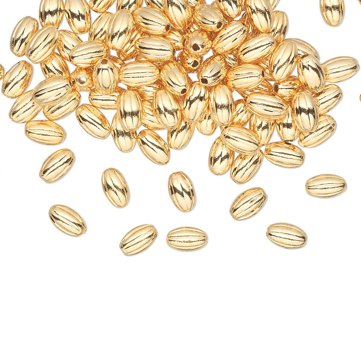 A pile of small metallic gold capsule-shaped beads scattered on a plain white background.