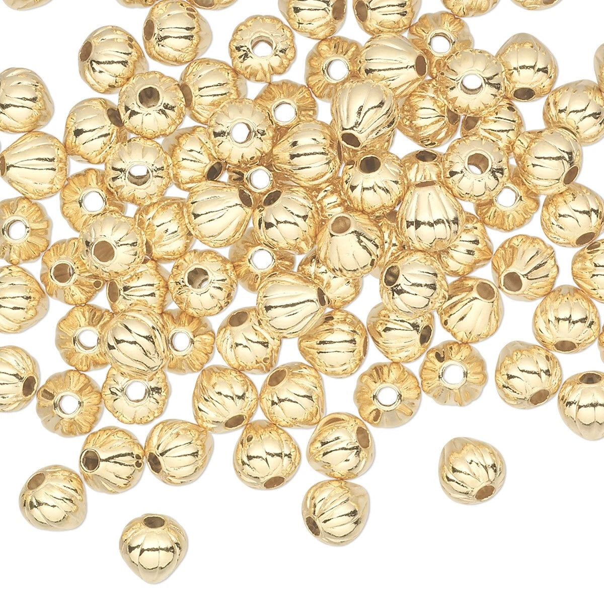 A pile of shiny gold metallic round beads with a ribbed texture and a central hole, scattered on a plain white background.