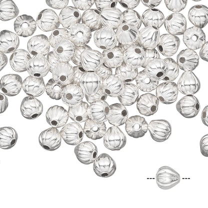 A pile of silver metallic conical beads with a ribbed texture and a central hole, shown on a white background with a single bead highlighted at the bottom right.