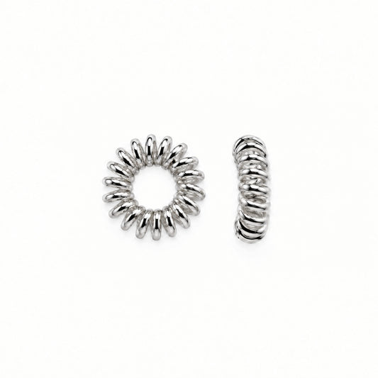 Two small silver-toned metal spacers, one circular with a sunburst pattern and one twisted coil-shaped, shown on a plain white background.