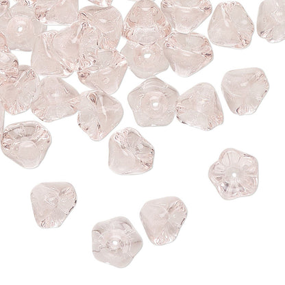 PINK glass flower-shaped beads scattered on a white background.