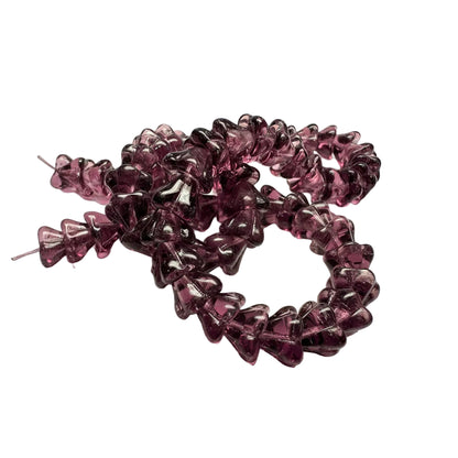A close-up of translucent purple glass chip beads arranged in a loose circle on a plain white background.