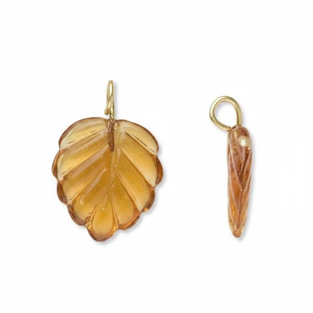 Two amber-colored leaf-shaped jewelry charms with gold-tone loops, shown on a plain white background.