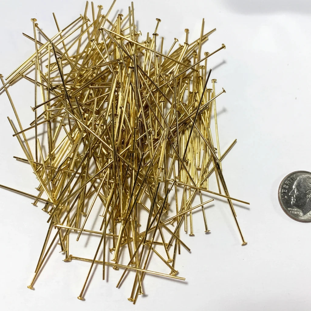 A pile of gold-colored metal push pins on a white background, with a US quarter coin on the right side for scale.