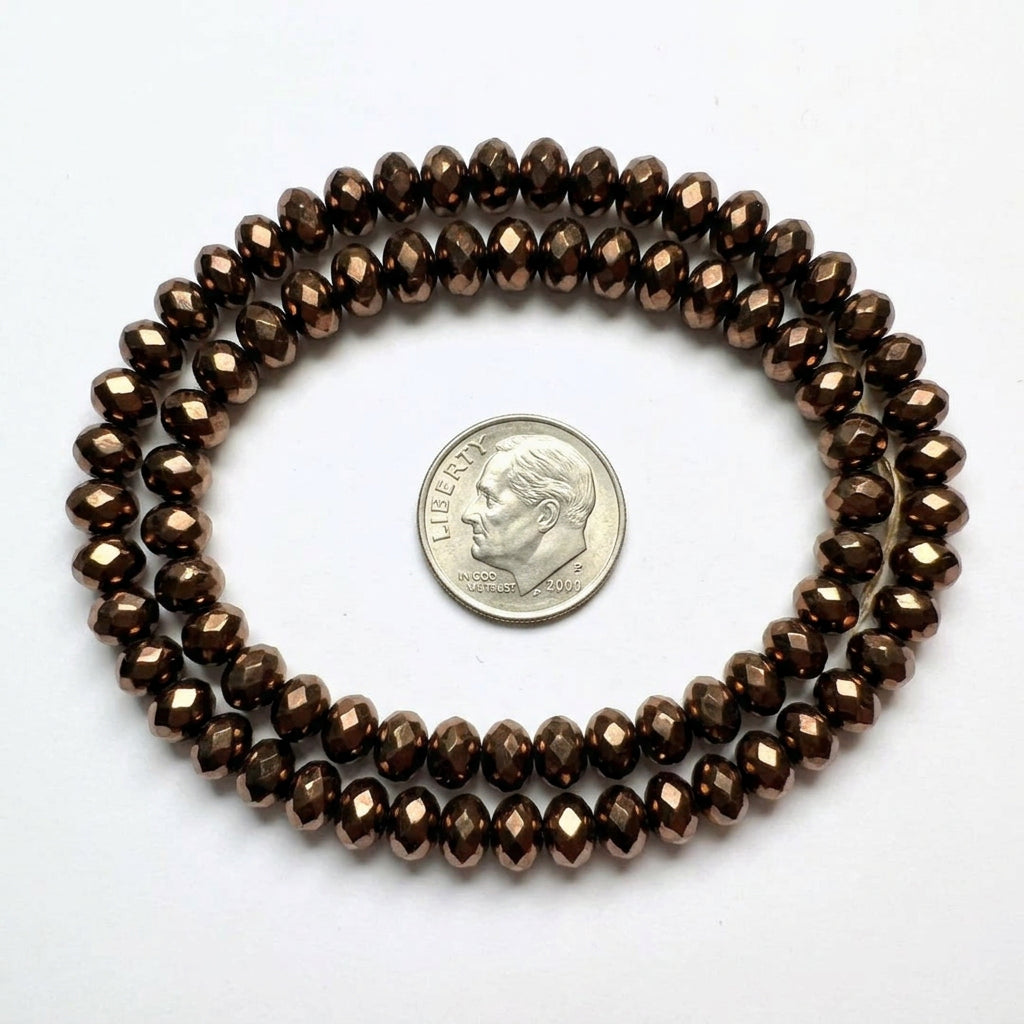 A strand of faceted dark brown beads, shown next to a US dime for scale, on a plain white background.