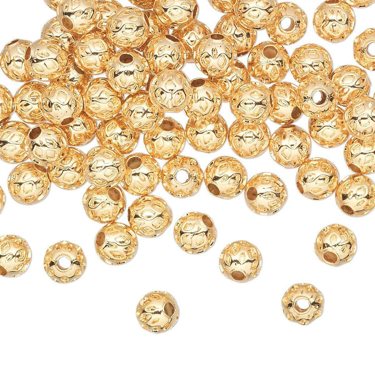 A pile of small round gold-toned beads with a textured, hammered surface and central holes, scattered on a plain white background.